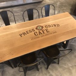 custom logo press & grind white oak plank table with steel banding accompanied with antique gold metal side chairs