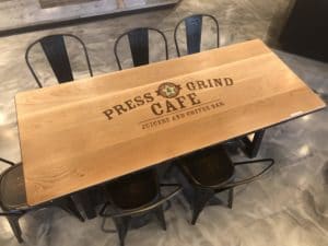 custom logo press & grind white oak plank table with steel banding accompanied with antique gold metal side chairs