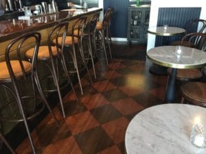 brass banded marble table tops paired with victorian bases, in Slay Steak + Fish House