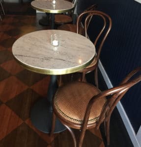 brass banded marble table tops paired with victorian bases, in Slay Steak + Fish House