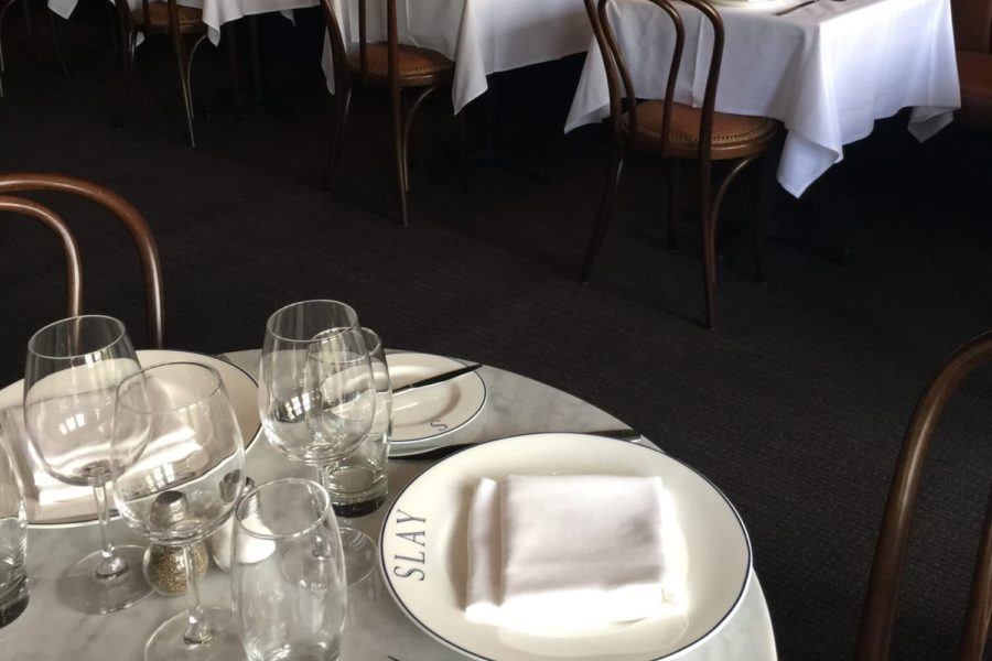 brass banded marble table tops paired with victorian bases, in Slay Steak + Fish House